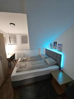a bedroom with a bed with a blue light at BK Apartment in Niš