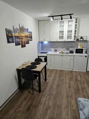 a kitchen with white cabinets and a table and chairs at BK Apartment in Niš
