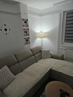 a living room with a couch and a clock on the wall at BK Apartment in Niš