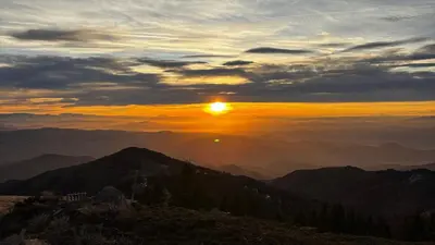 a sunset on top of a mountain with the sun setting at Monte LUX 10 in Kopaonik