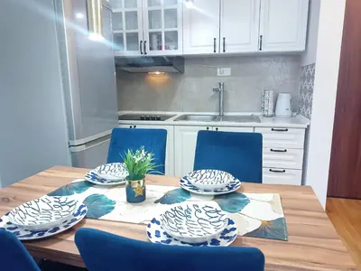 a kitchen with a wooden table with blue chairs at Magnolia Lux Apartments - komplex Green Hill in Soko Banja