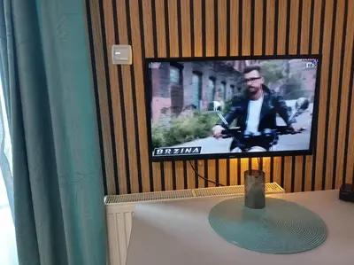 a tv screen on a wall with a table and a table sidx sidx at Magnolia Lux Apartments - komplex Green Hill in Soko Banja