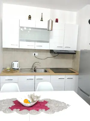 a kitchen with white cabinets and a bowl of fruit on a table at Magnolia Lux Apartments - komplex Green Hill in Soko Banja