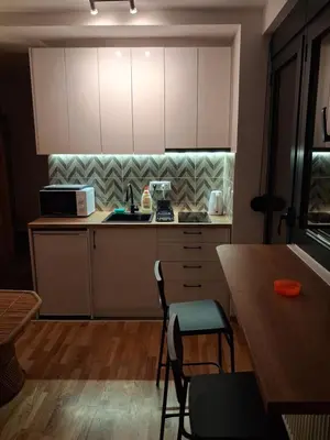 a kitchen with white cabinets and a wooden table at Centar Crnjanski 2 in Jagodina