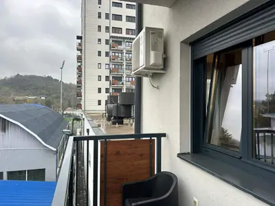 a balcony of a building with a window and a chair at Centar Crnjanski 2 in Jagodina