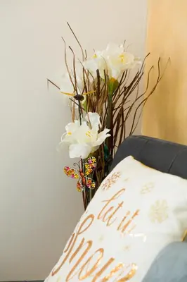 a vase of white flowers sitting next to a pillow at Apartman Lusi Vranje in Vranje