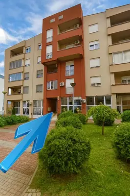 a building with a blue arrow in front of it at Apartman Lusi Vranje in Vranje