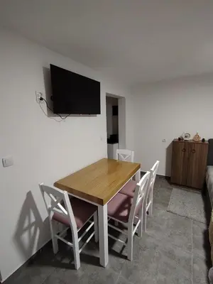 a dining room table with chairs and a television on a wall at Everblue Chalet Kopaonik in Kopaonik