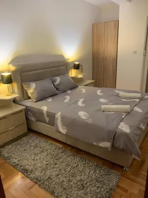a bedroom with a bed with a gray comforter and a rug at City Comfort Apartment in Vranje