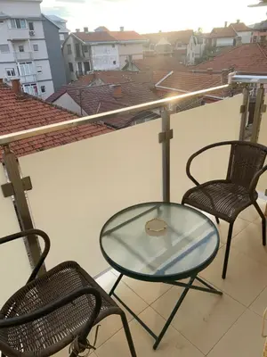 a glass table and two chairs on a balcony at City Comfort Apartment in Vranje