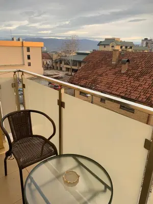 a glass table and a chair on a balcony at City Comfort Apartment in Vranje