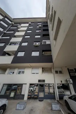 a tall building with cars parked in a parking lot at NAR Royalton Apartment #27 Free Parking in Niš
