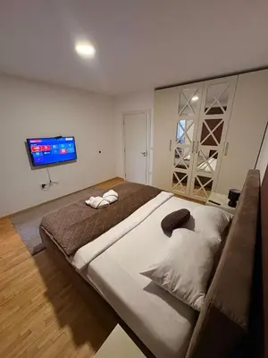 a bedroom with a large bed and a flat screen tv at NAR Royalton Apartment #27 Free Parking in Niš