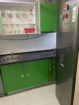 a kitchen with green cabinets and a stainless steel refrigerator at Panorama Bulevar in Niš