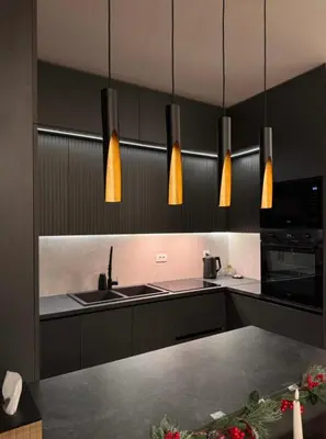 a kitchen with black cabinets and a sink and pendant lights at Riviera Suite in Niš