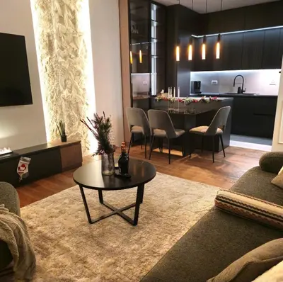 a living room with a table and a kitchen at Riviera Suite in Niš