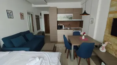a kitchen and a living room with a table and blue chairs at Blistava Dolina S42 in Kopaonik