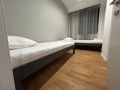 a bedroom with two beds and a wooden floor at Tokyo88 Apartment in Niš