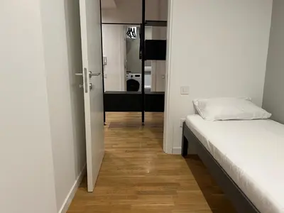 a room with a bed and a hallway with a mirror at Tokyo88 Apartment in Niš