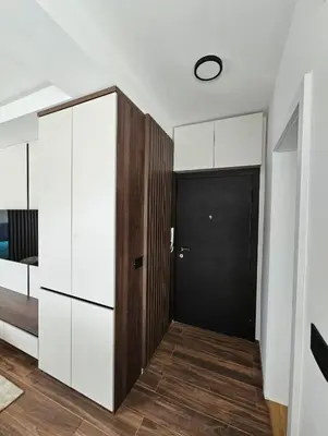a hallway with a black door and white cabinets at Apartman Vrabac in Vrnjačka Banja