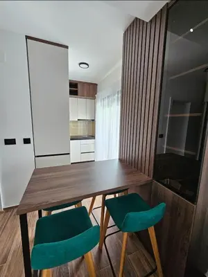 a kitchen with a wooden table and two green chairs at Apartman Vrabac in Vrnjačka Banja
