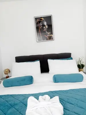 a bed with blue and white pillows on it at Apartman Akva Park in Trnava