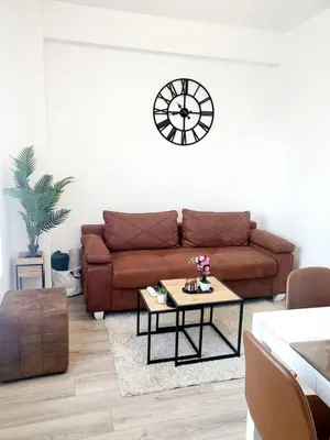 a living room with a brown couch and a clock on the wall at Apartman Akva Park in Trnava