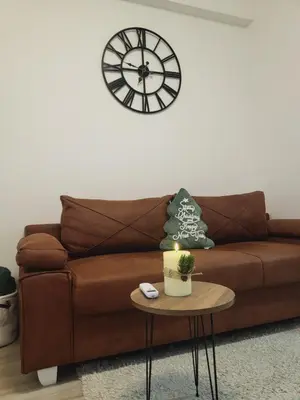 a living room with a brown couch and a clock at Apartman Akva Park in Trnava