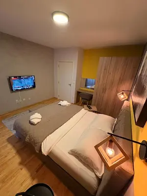 a bedroom with a large bed and a television at NAR Royalton Apartment #76 Free Parking in Niš