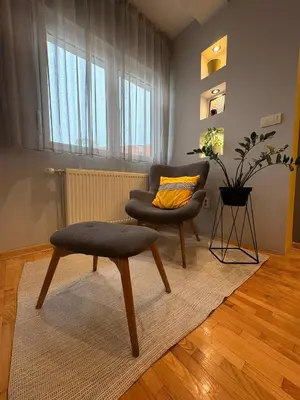a living room with a chair and a ottoman at NAR Royalton Apartment #76 Free Parking in Niš