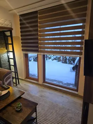 a living room with a large window with blinds at Prime NG Mujen lux & spa in Cajetina