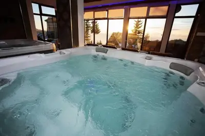 a jacuzzi tub with a view of the sunset at Prime NG Mujen lux & spa in Cajetina