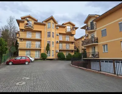 a building with a car parked in a parking lot at Apartman Štekić in Vrnjačka Banja