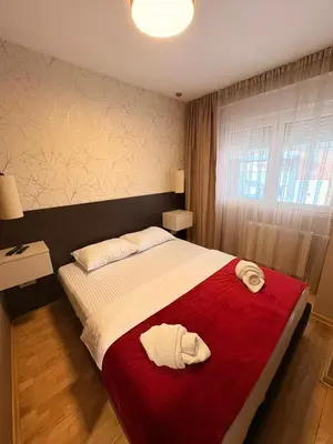 a bedroom with a large bed with two towels on it at NAR Royalton Apartment #01 Free Parking in Niš