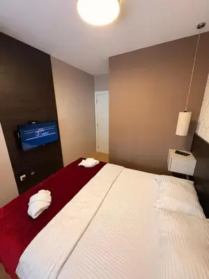 a bedroom with a bed and a tv on a wall at NAR Royalton Apartment #01 Free Parking in Niš
