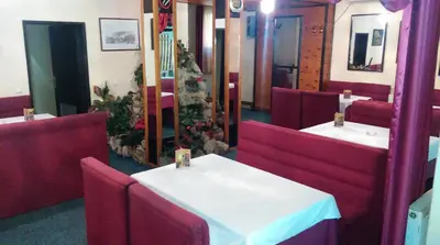 a dining room with a white table and red chairs at Bed & Breakfast Karavan in Raška