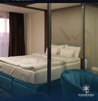 a bedroom with a bed and a blue chair at DZAT apartman, Harmonija Hotel in Kopaonik