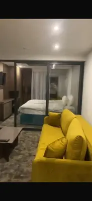 a yellow couch in a room with a bed at DZAT apartman, Harmonija Hotel in Kopaonik