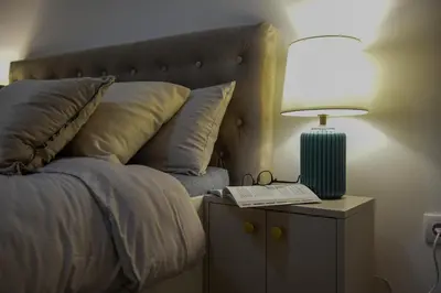 a bed with a lamp and a book on a night stand at Apartman P Lux 1 Ćuprija in Ćuprija