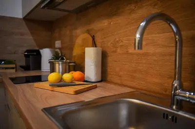 a kitchen counter with a sink and fruit on a cutting board at Apartman P Lux 1 Ćuprija in Ćuprija