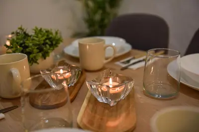 a table with glasses and plates and candles on it at Apartman P Lux 1 Ćuprija in Ćuprija