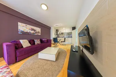 a living room with a purple couch and a tv at NAR Royalton Deluxe Apartment #40 Free Parking in Niš