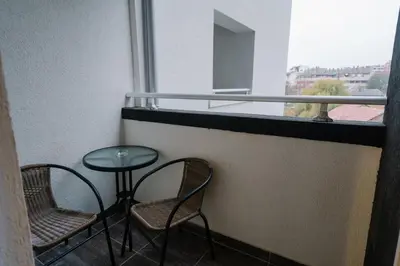 a balcony with two chairs and a table and a window at NAR Royalton Deluxe Apartment #40 Free Parking in Niš