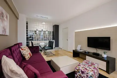 a living room with a purple couch and a tv at NAR Royalton Deluxe Apartment #40 Free Parking in Niš