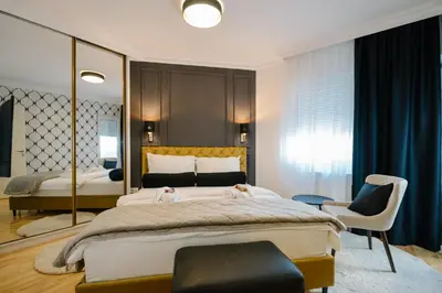 a bedroom with a large bed and a chair at NAR Royalton Deluxe Apartment #63 Free Parking in Niš