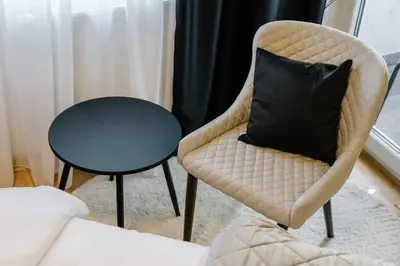 a chair with a black pillow sitting next to a table at NAR Royalton Deluxe Apartment #63 Free Parking in Niš