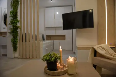 a living room with a table with a candle and a tv at Apartman P Lux 2 Ćuprija in Ćuprija