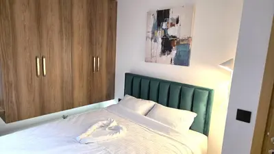 a bedroom with a bed with white sheets and wooden cabinets at Sunny Hill Kop - Luxury Apartment Mountain View in Kopaonik