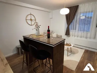 a kitchen with a bar with chairs and a bottle of wine at Apartman Herkul in Kopaonik