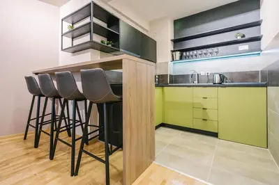 a kitchen with black and green cabinets and stools at NAR Royalton Apartment #60 Free Parking in Niš